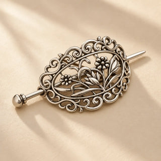 A vintage silver floral hair barrette inspired by the Mona Lisa art edition, photographed on a warm ivory background.