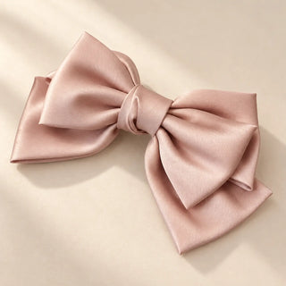 A blush pink satin bow hair accessory inspired by The Swing art edition, styled against a soft ivory background.