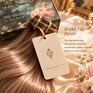 A cream Full Shine brand tag with the signature diamond emblem attached to a light brown hair extension bundle inspired by The Swing.